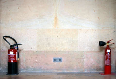 The photograph of two fire extinguishers on a wall            の写真素材