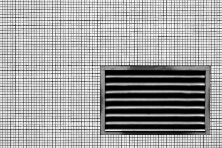 The photograph of a ventilation grille on a wall with mosaic tiles             の写真素材