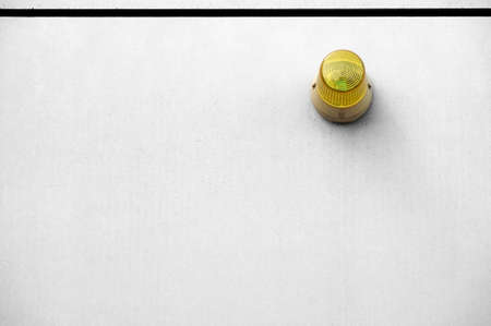 The photograph of a yellow warning light on a smooth concrete wall.の写真素材