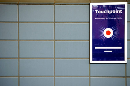 A touch point for mobile phones on a tiled wall of a railway station.