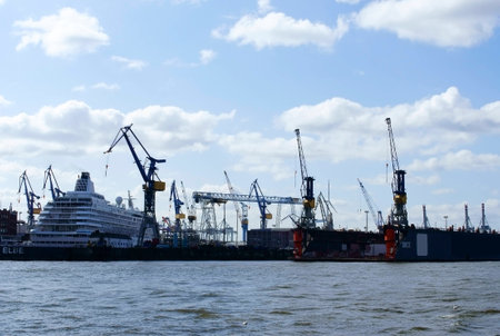 A large cruise ship in a dock and harboir is surrounded by cranes.の写真素材