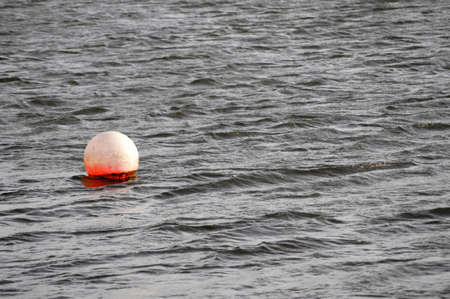 A ball-shaped red buoy floating on the water.の写真素材