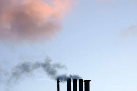 Smoking chimneys or pipe ends in front of an evening sky.の写真素材