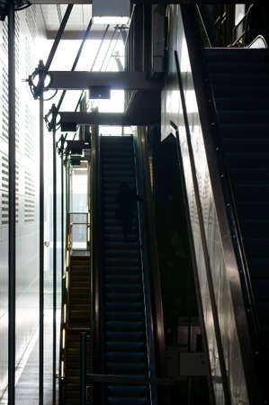 A woman silhouette climbs up an escalator.