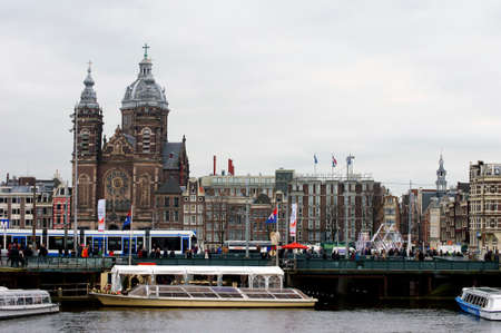 Amsterdam, The Netherlands - December 30, 2014: Group of people walking over a bridge with boats in front of the Basilica of St. Nicholas on December 30, 2014 in Amsterdam.のeditorial素材