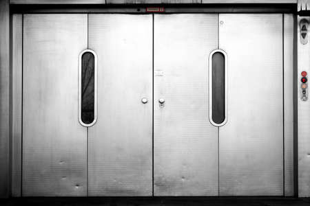 A freight elevator with heavy sliding doors on level zero, the ground floor.