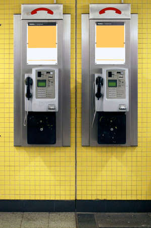 Two old nostalgic payphones hanging on the tiled wall of a subway tunnel.の写真素材