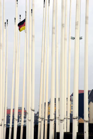 A German flag waving between closely juxtaposed flagpoles.の写真素材