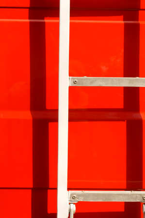 The closeup of a body of a fire truck in the sunshine with a ladder, which casts a shadow.の写真素材