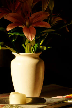 The low key photograph of a bouquet in a white vase with flowers and a candlestick.の写真素材