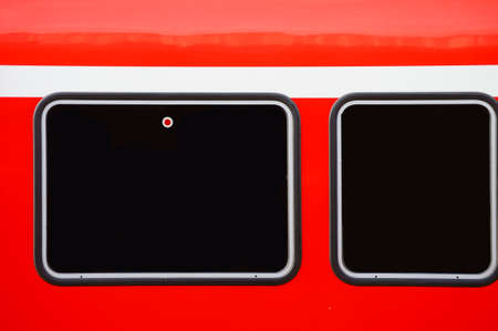 The closeup of the outer body of a passenger train with two windows.
