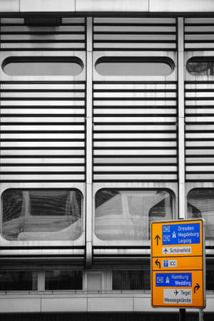 A yellow highway sign or street sign stands in front of a striking facade made of metal.の写真素材