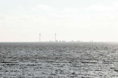 The sea, the Ijsselmeer in the Netherlands with an island and wind turbines on it.の写真素材