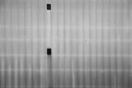 A striking and corrugated metal facade with two ventilation grilles.