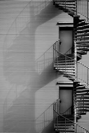 A spiral staircase, fire escape on the side of a industrial building facade.の写真素材