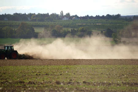 A tractor with a plow dust on the dry ground.の写真素材
