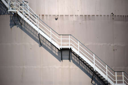 The top of a water tank with a walk-ladder that casts a shadow.