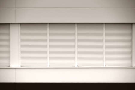 A number of modern windows of a business building with closed blinds.