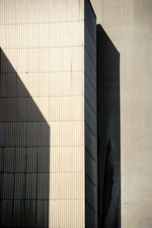 The corners and edges of an industrial building cast geometric shadows.の写真素材