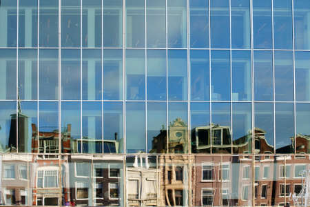 An abstract mirrored row of houses in the windows of a modern office building.