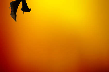 The detail of women's legs with high heels in front of a flame-colored background.の写真素材