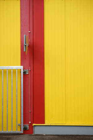 A colorful and striking sidewall of a shopping center with a part of an access gate and a road sign.の写真素材