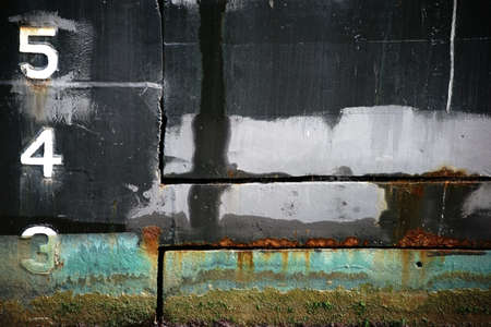 The closeup of a rusty and with algae overgrown vessel wall of a tanker.