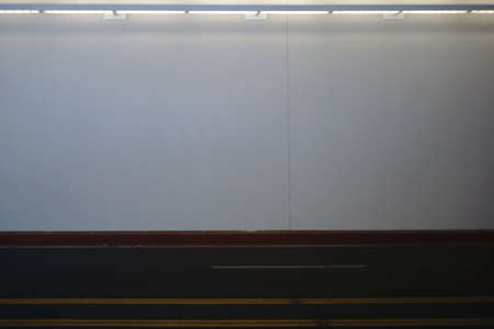 The illuminated and homogeneous wall of an underpass with an adjacent road marking.