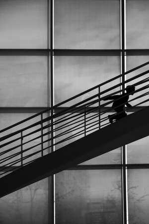The silhouette of a boy of a staircase rises in a stooped posture.の写真素材