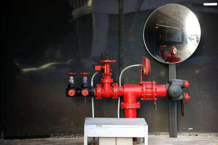 Fire water connections in signal red color on a driveway with a traffic mirror.