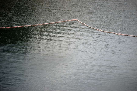 A chain of floating buoys used as a barrier or demarcation.