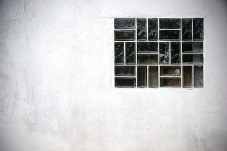 The close-up of a window on a cracked wall with glass tiles.の写真素材
