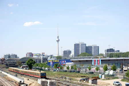 Berlin, Germany - May 09, 2016: Two Berlin suburban trains leaving a train station with a domed roof and the Berlin TV Tower in the background on May 09, 2016 in Berlin.のeditorial素材