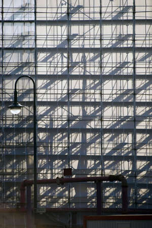 The Pipes and wooden inserts from a scaffolding cast abstract shadows on a plastic sheet.の写真素材