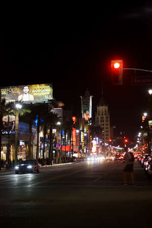 Los Angeles, United States - December 27, 2015: A pedestrian crosses a traffic light at the night lit Hollywood Boulevard with traffic on December 27, 2015 in Los Angeles.のeditorial素材