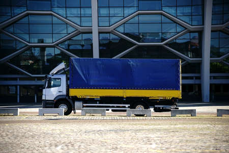 The side profile of a truck in front of a modern glass facade.