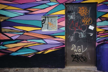 Mainz, Germany - October 19, 2015: A colorful graffiti painted house wall with an iron door in a...