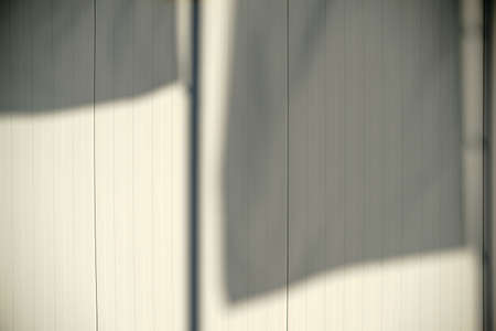 The close-up of waving flag shadows on a beige corrugated facade.の写真素材