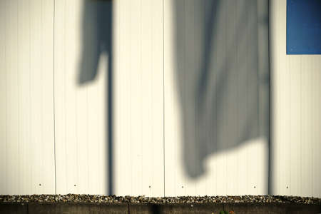 The close-up of waving flag shadows on a beige corrugated facade.の写真素材