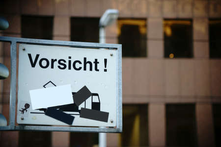 A signboard almost covered with stickers, caution tram, at a traffic light.の写真素材