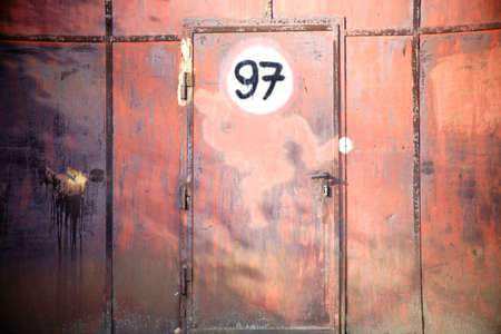 A rusted iron gate with a door and a sign.の写真素材