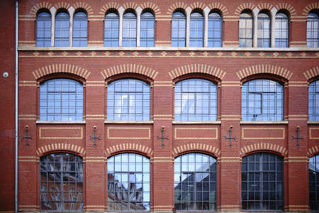 The exterior facade of a brick building with large lead windows.                          の写真素材