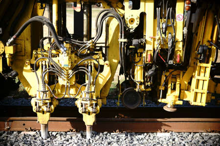 The close-up of the hydraulics and lifting cylinders of a tamping machine and straightening machine in track construction.              の写真素材