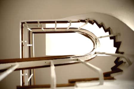 The underview of a staircase with a spiral staircase and railings.