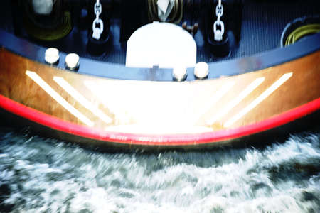 The foaming water of a river in front of the bow of a transport vessel.の写真素材