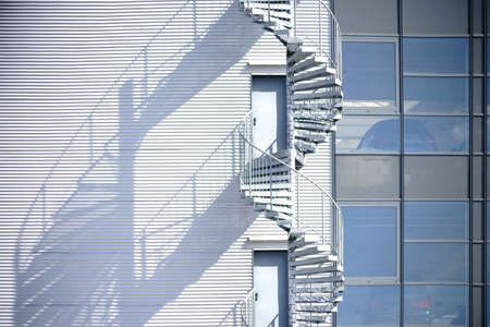 A spiral staircase, fire escape on the side of a industrial building facade.の写真素材