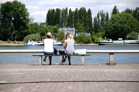 Mainz, Germany - June 26, 2017: Two young unknown women sitting on a park bench at river Rhine on June 26, 2017 in Mainz.のeditorial素材
