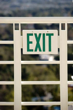 An exit sign with the letters exit at a railing.
