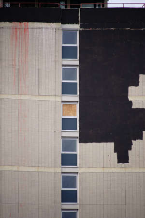 The side view of a high-rise building with tiled facade and color improvements of damaged areas.の写真素材