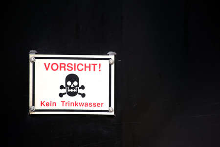 A warning sign with skull and red letters against a black background.の写真素材